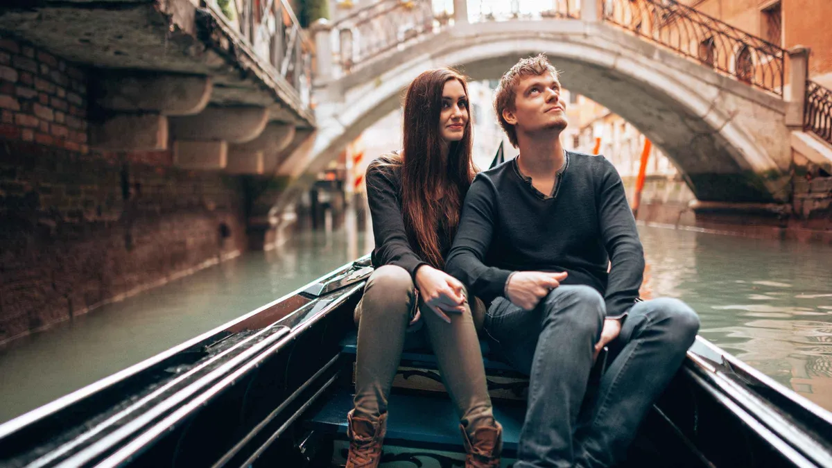 Couple photographed from a private gondola during a Venice photoshoot on the canals, gondolier at the stern