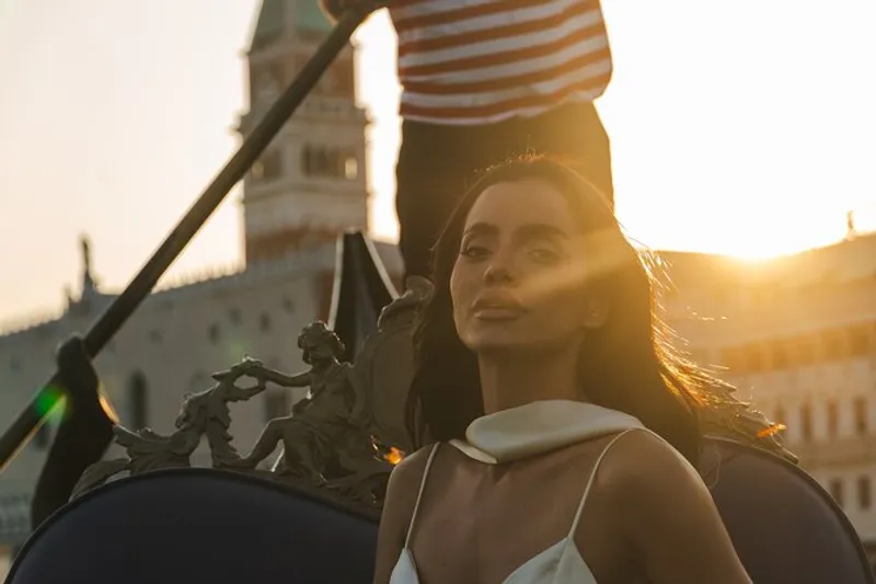 Woman photographed on a gondola at golden hour during a cinematic photoshoot venice session near St Mark's