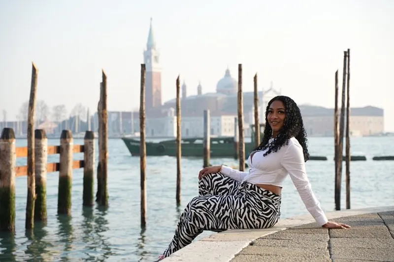 Solo traveler seated at the lagoon waterfront with San Giorgio Maggiore behind during a venice instagram photoshoot